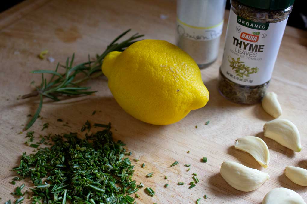chopped herbs, lemon, garlic and dried herbs on cutting board