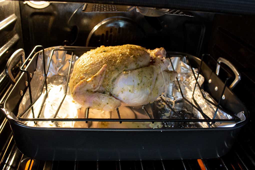 chicken on rack inside roasting pan in oven