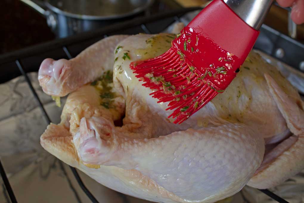 brushing garlic herb-butter on chicken