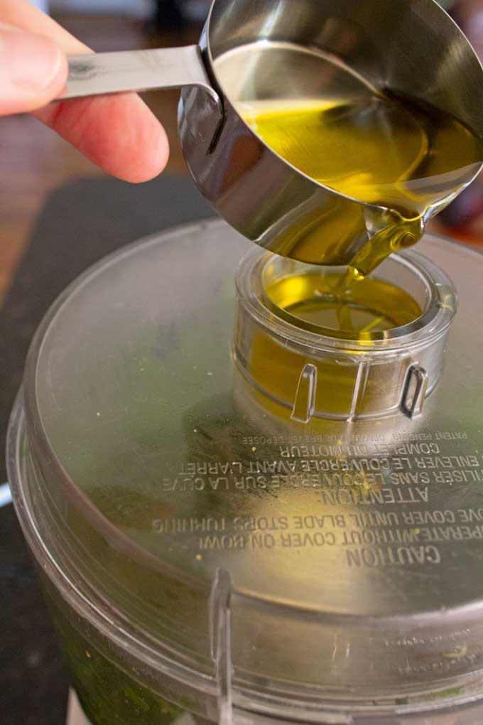 pouring olive oil into drizzle spout of food processor