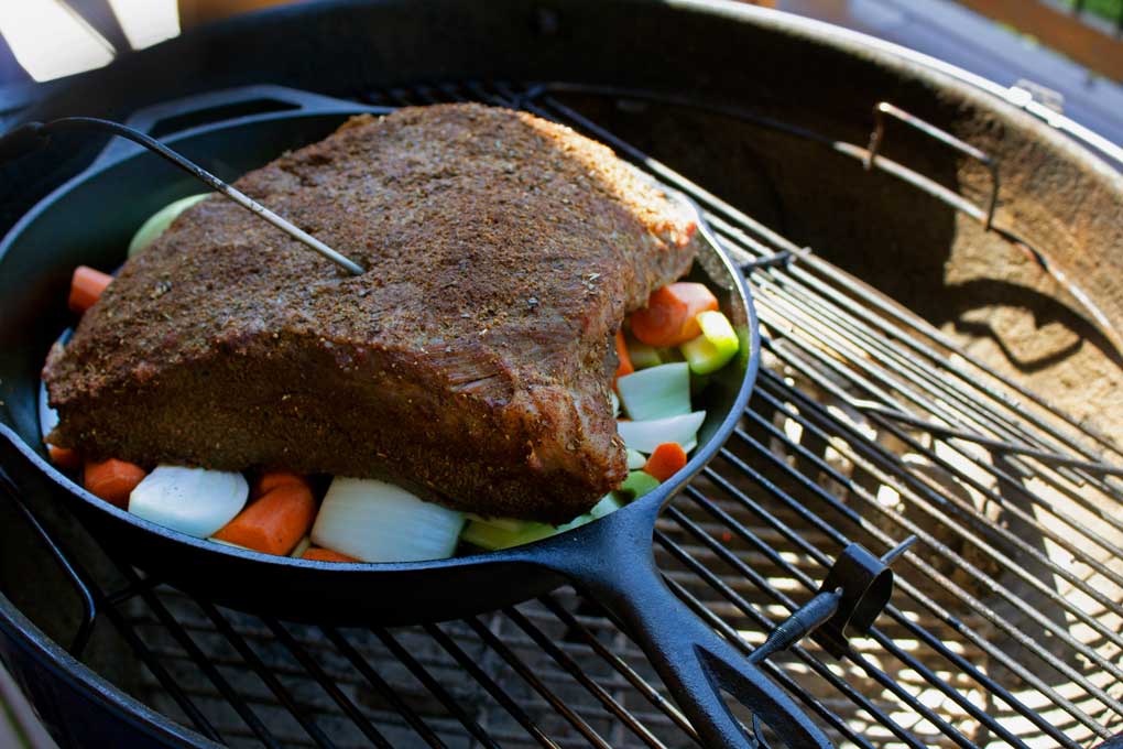 brisket in cast iron pan on grill