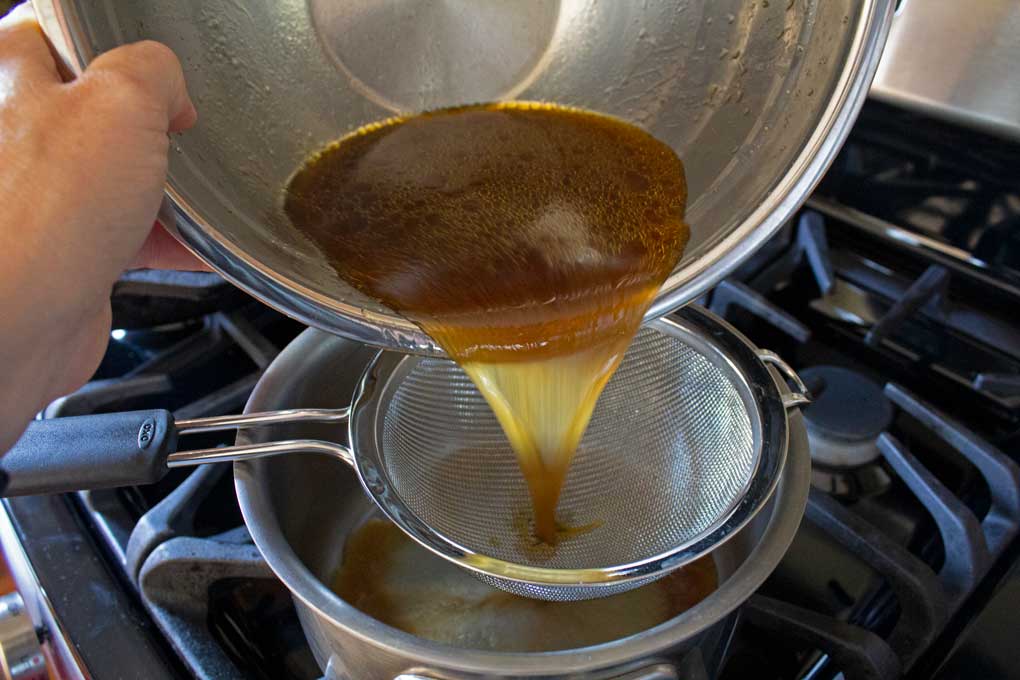 pouring au jus through sieve