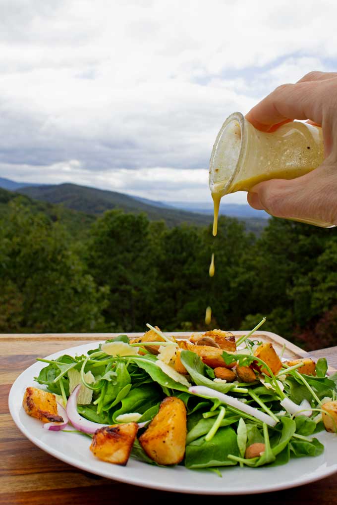 drizzling dressing onto butternut squash arugula salad