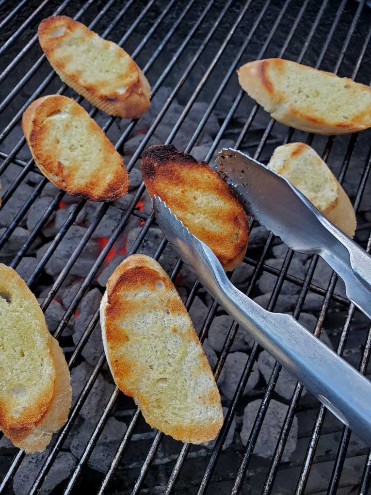 tossing grilled toast with tongs for grilled tomato soup