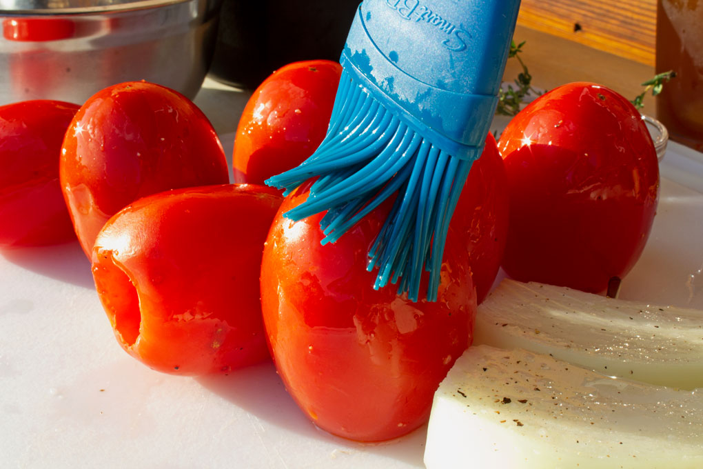brushing oil onto tomatoes and onions