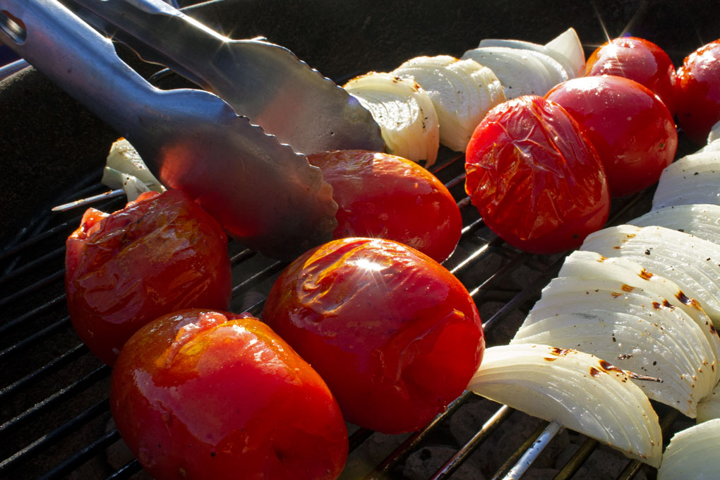 tossing the tomatoes for grilled tomato soup with tongs