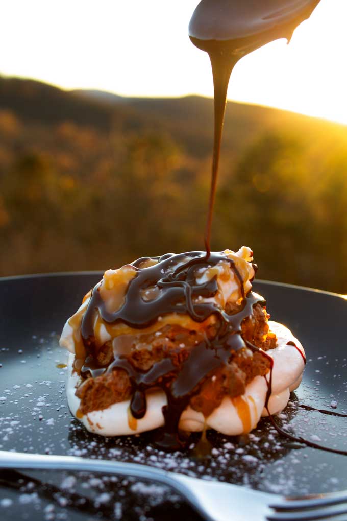 drizzling chocolate sauce over chocolate mousse pavlova