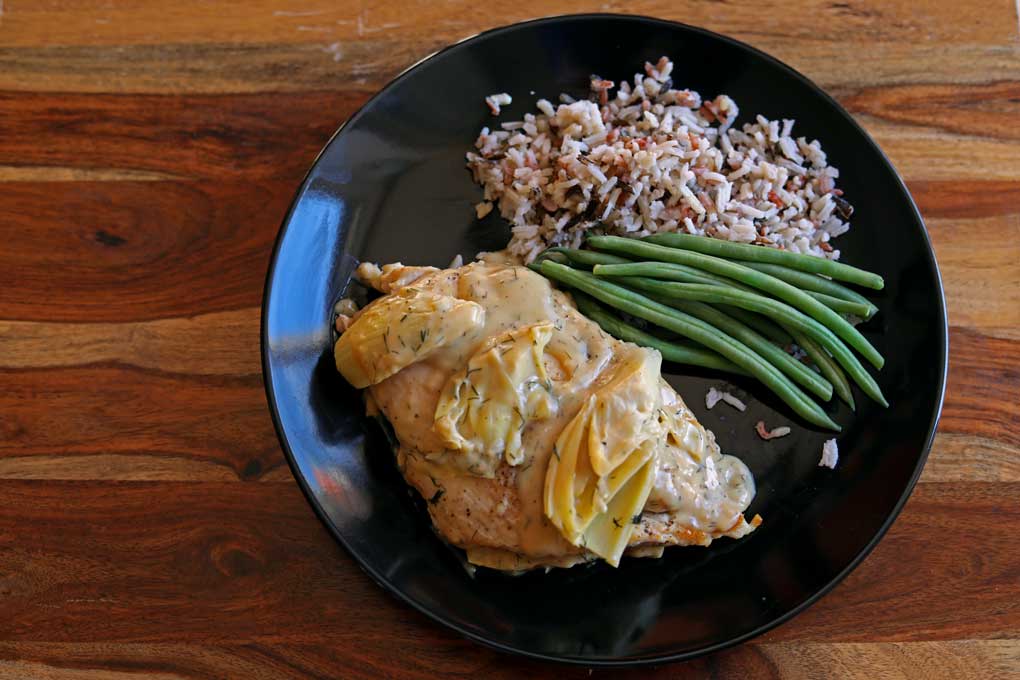 chicken and artichokes with lemon dill cream sauce on plate with rice and green beans