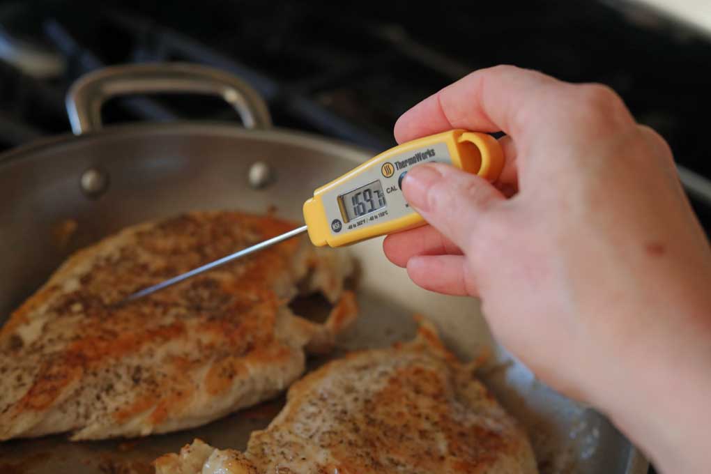 checking temperature of chicken with instant-read thermometer