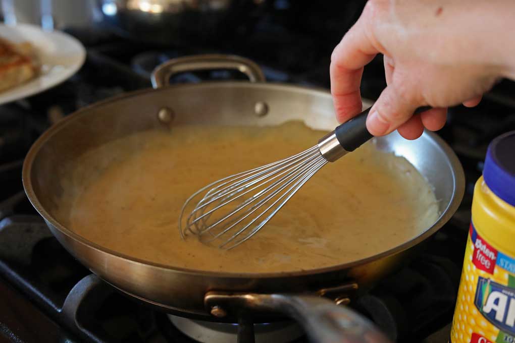 whisking cream sauce in skillet