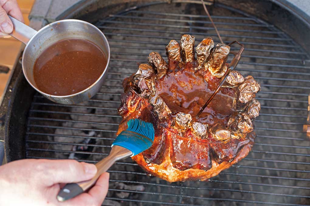 brushing the smoked pork crown roast with bbq sauce