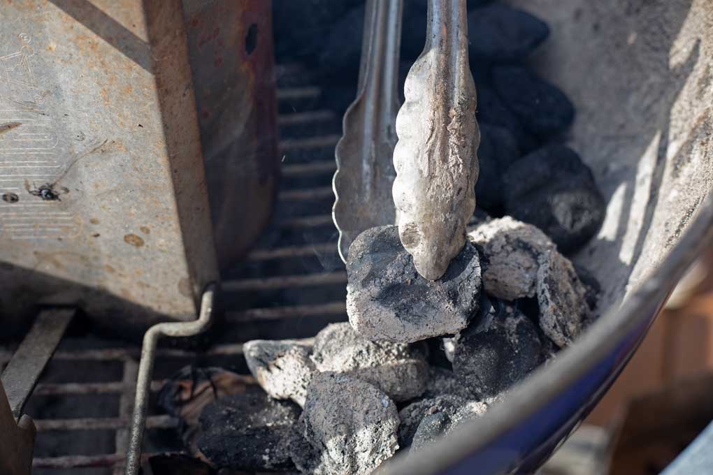 tongs dropping hot coals onto charcoal snake