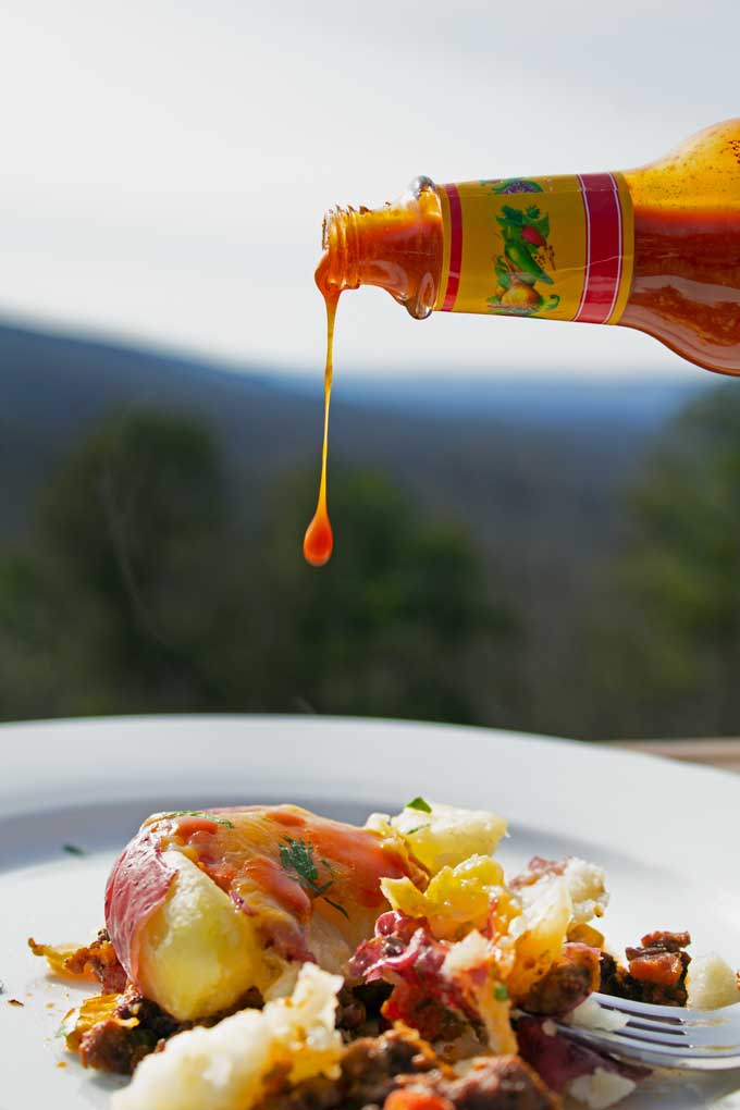 pouring hot sauce onto good shepherd's pie
