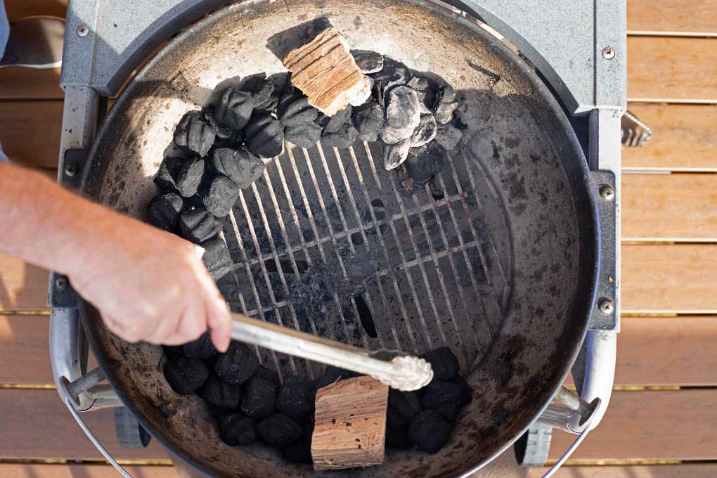 setting up charcoal and wood inside grill