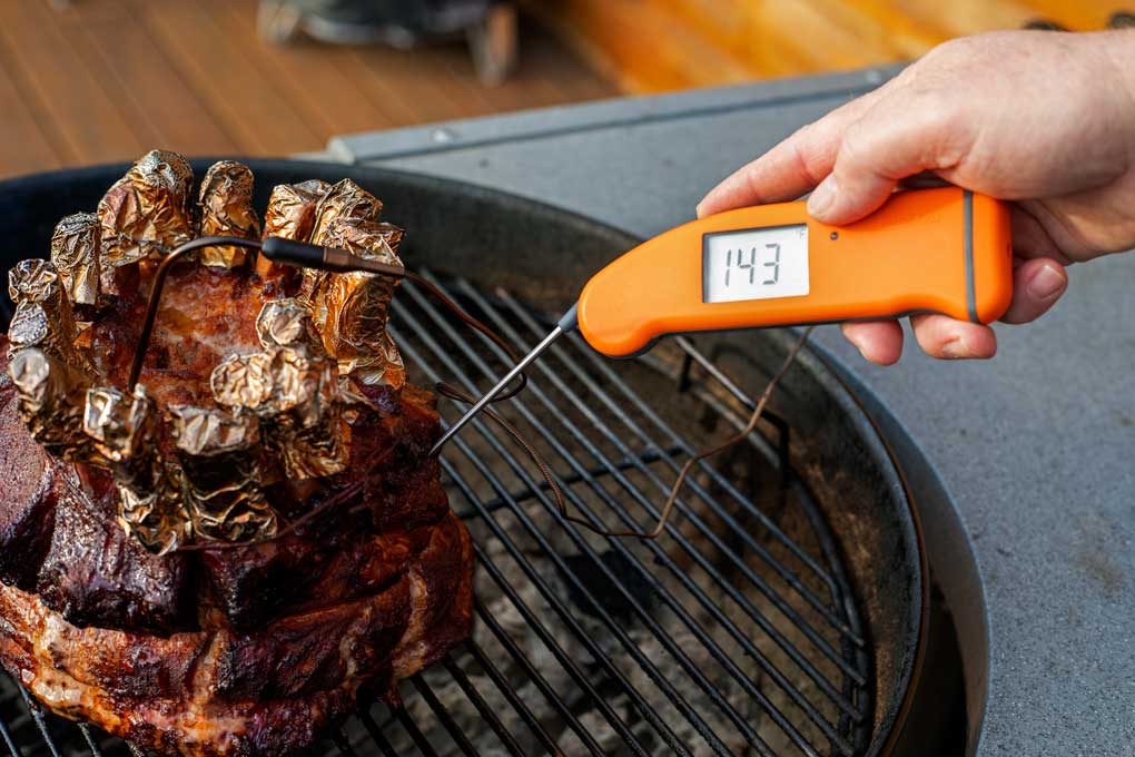checking temperature of the smoked pork crown roast with Thermapen