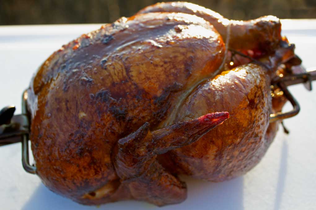 rotisserie-smoked chicken resting on carving board