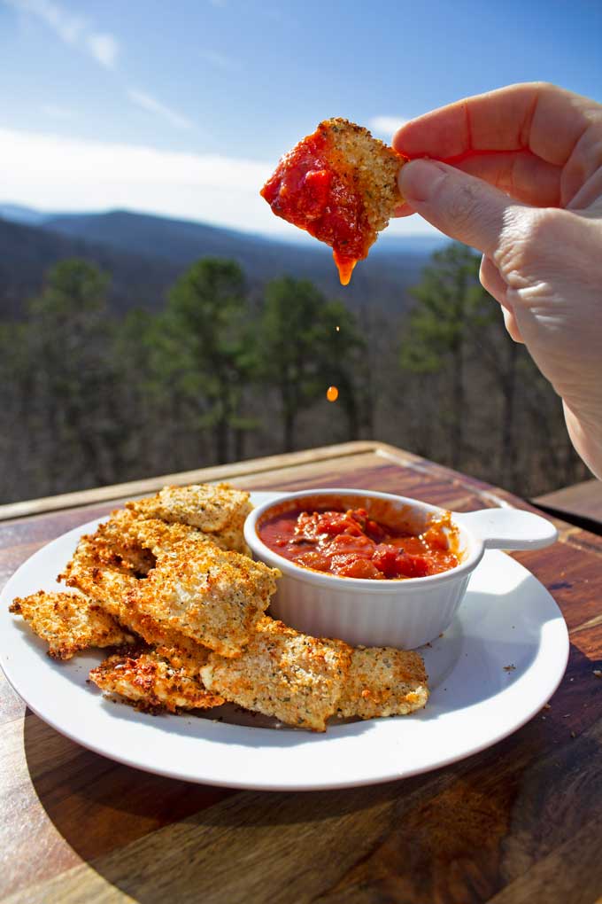 air fryer ravioli with quick tomato dipping sauce dripping off ravioli