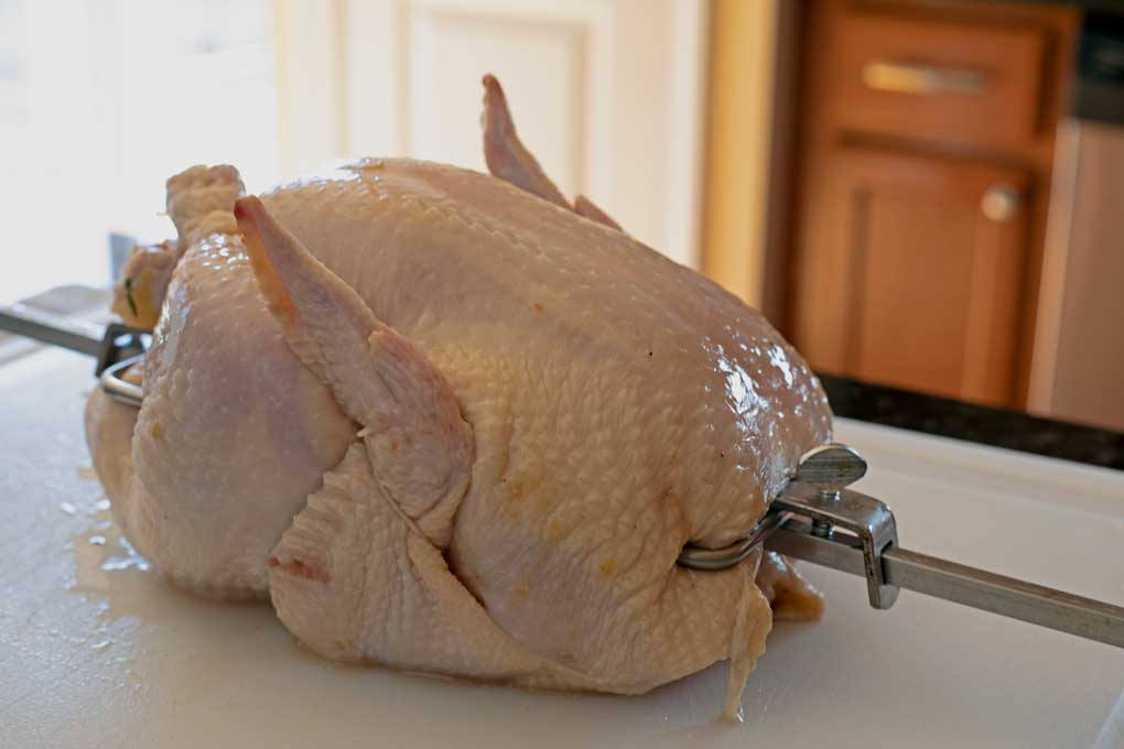 raw whole chicken on spit