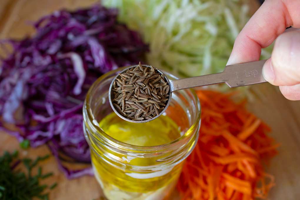 teaspoon of caraway seeds over jar and chopped veggies