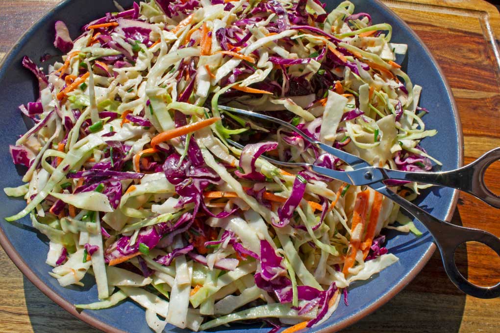 easy coleslaw in bowl with tongs