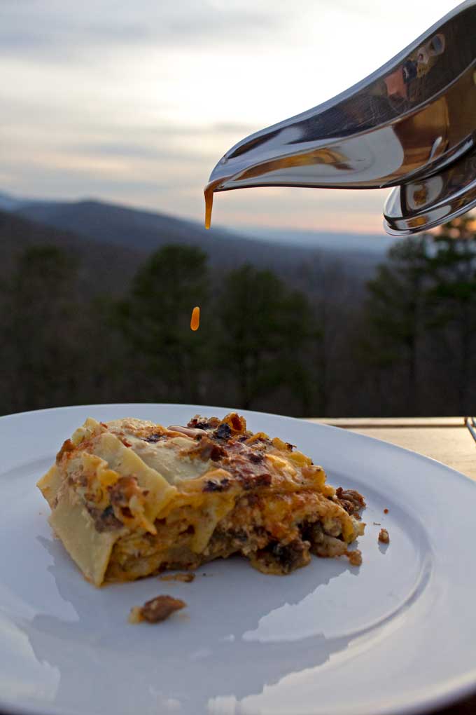 drizzling bbq sauce onto smoked brisket lasagna