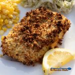 prepared air fryer cod on plate with lemon wedge, corn and slaw