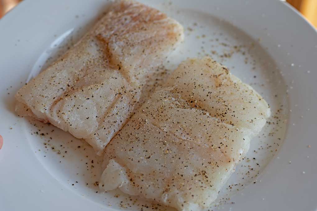 salt and peppered cod fillets on plate