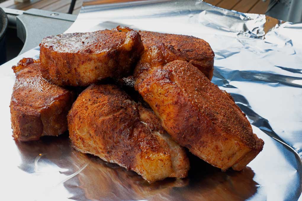 smoked pork chops piled up on foil