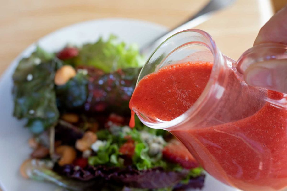 pouring strawberry vinaigrette over salad