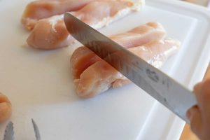 knife cutting chicken into cubes