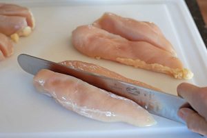 knife cutting chicken breast in half