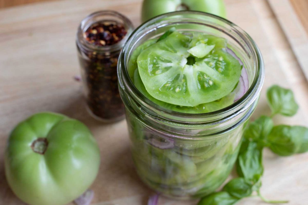 pickled green tomatoes in jar with other ingredients