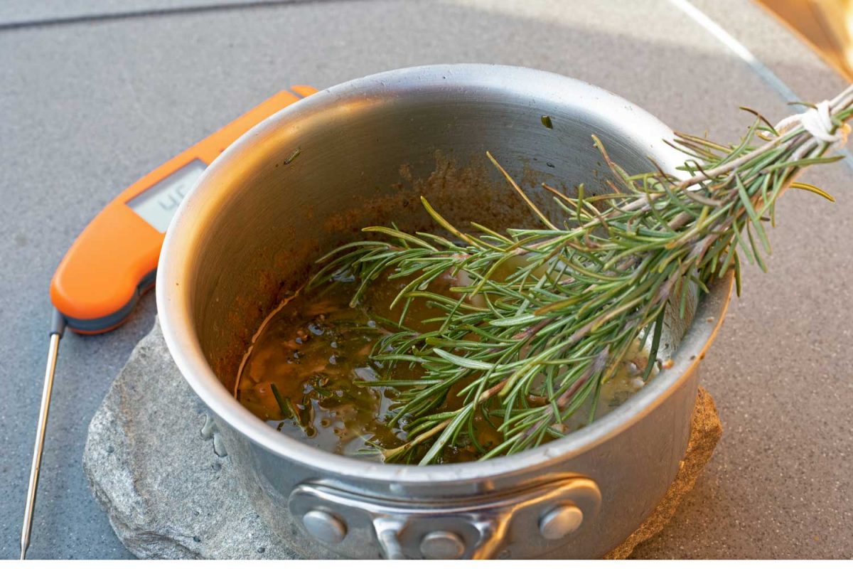 garlic herb basting butter with rosemary brush in pot beside thermapen on table