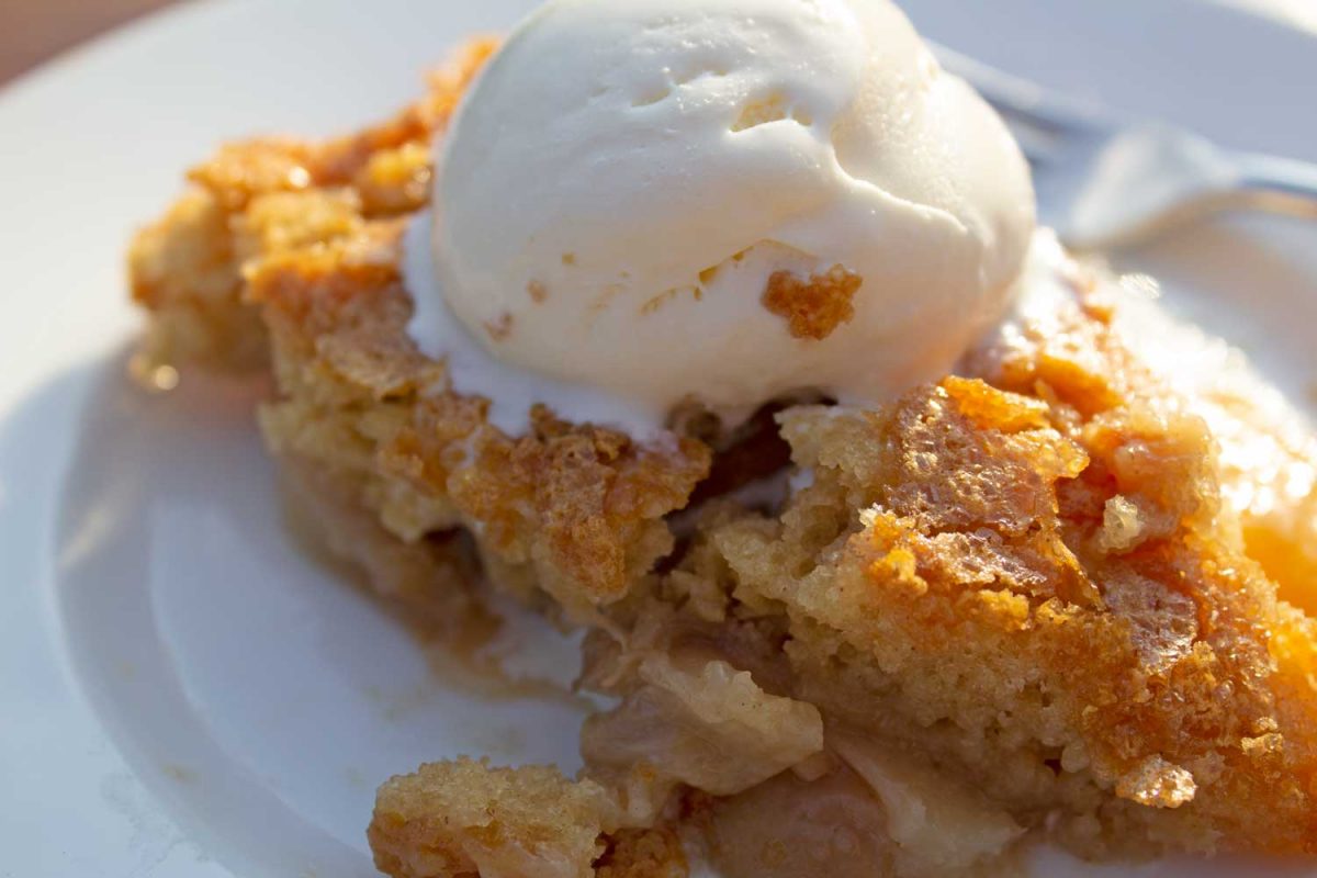peach skillet cake with scoop of melting vanilla ice cream