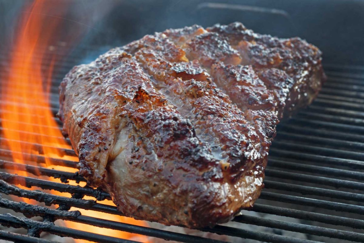 flames licking meat on grill