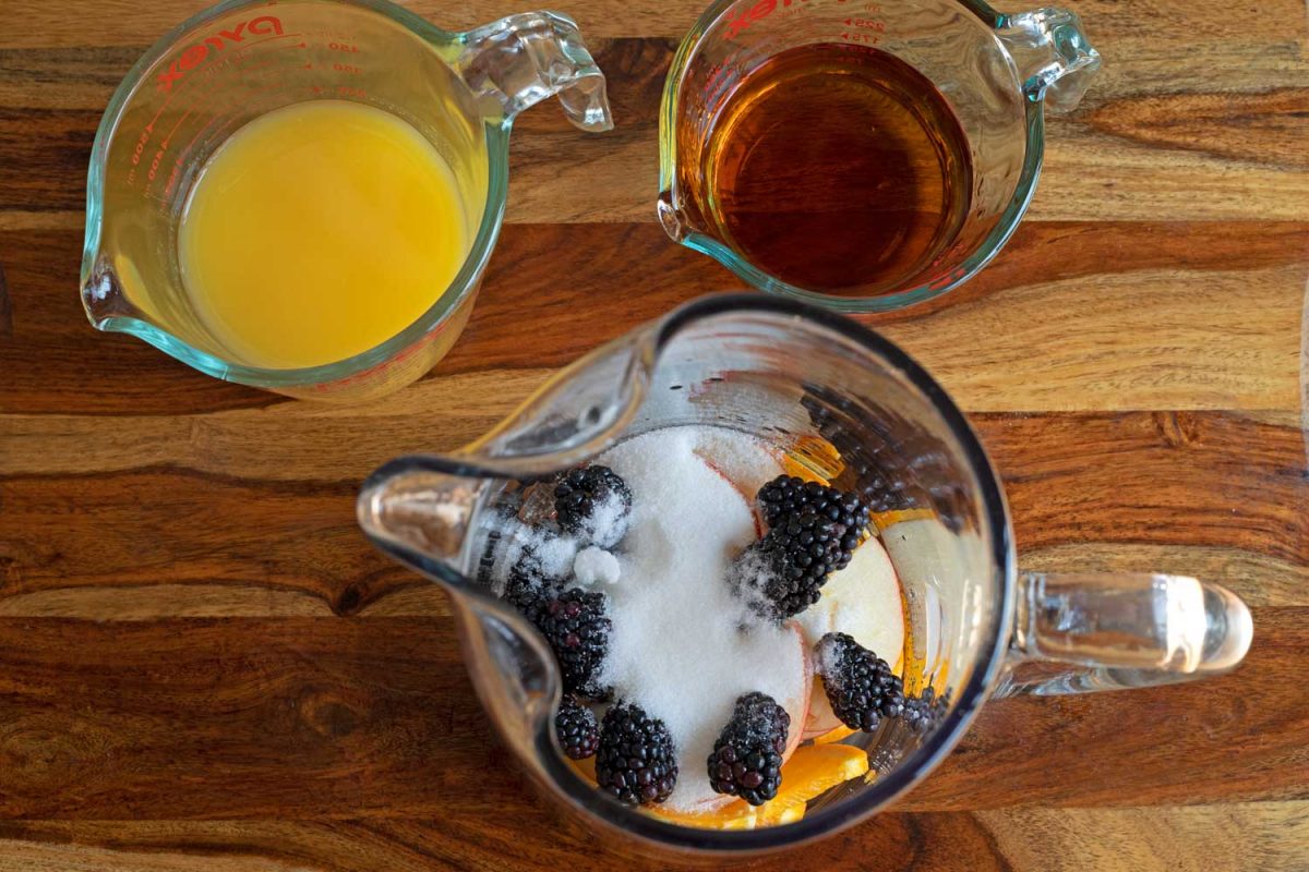 cup of orange juice, cup of brandy, pitcher of fruit and sugar