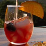 the best sangria being poured into glass with fruit