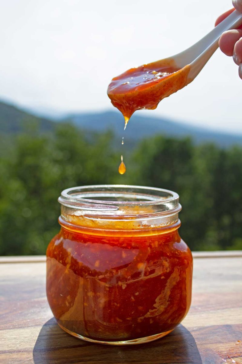spoon of Thai sweet chili sauce dripping into jar