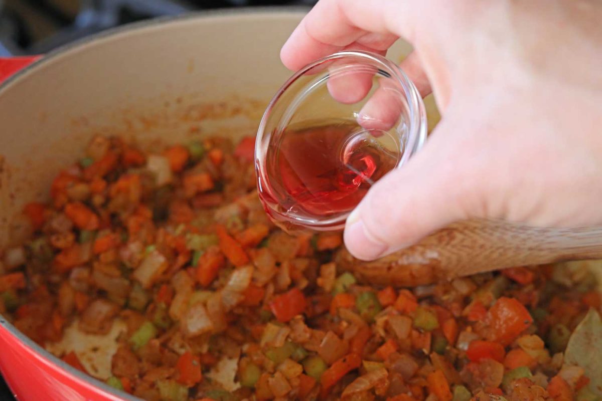 pouring vinegar into pot of vegetables