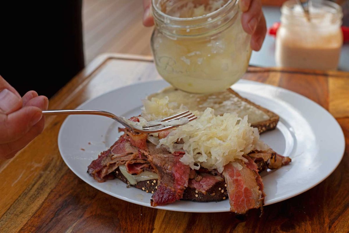 putting sauerkraut on sandwich