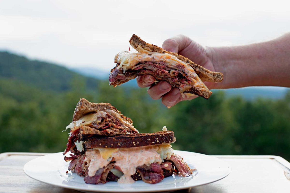 hand holding pastrami Reuben andwich
