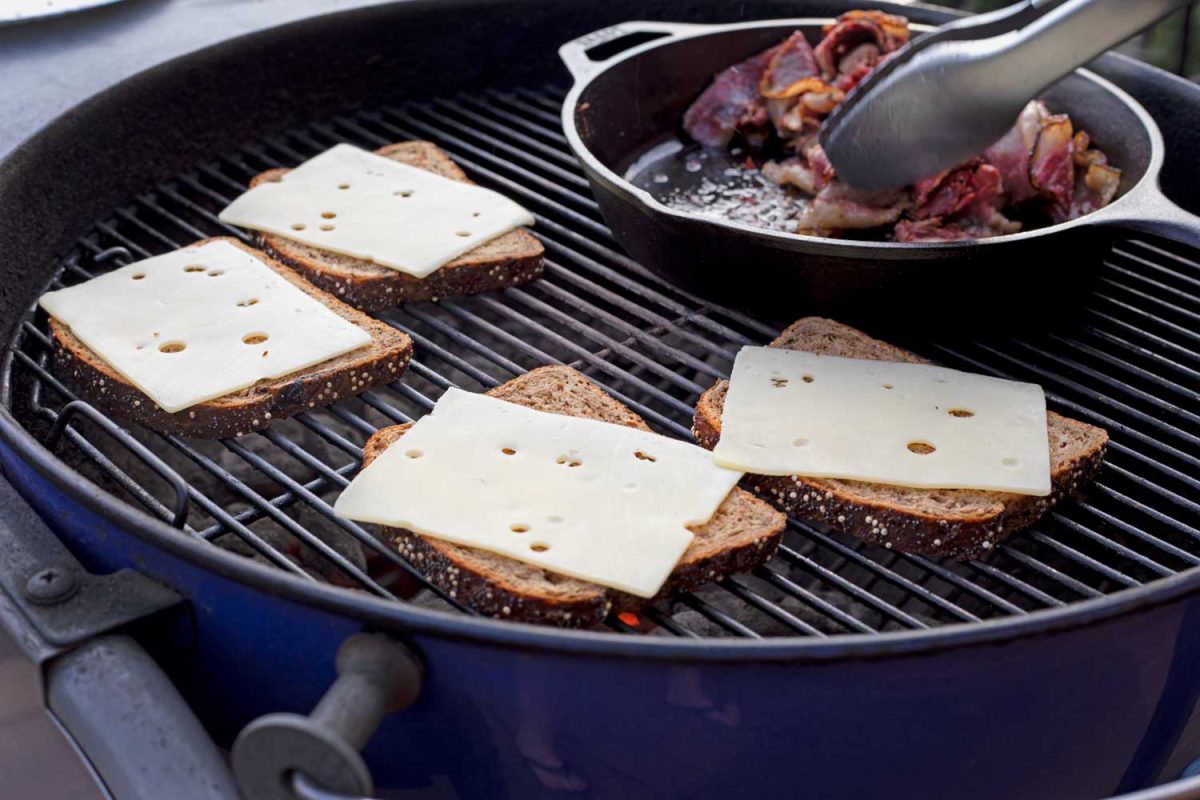 toasting rye bread with Swiss cheese slices on grill