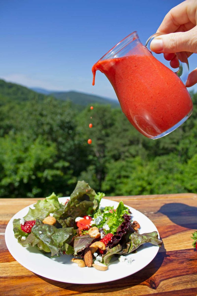 drizzling strawberry vinaigrette over salad