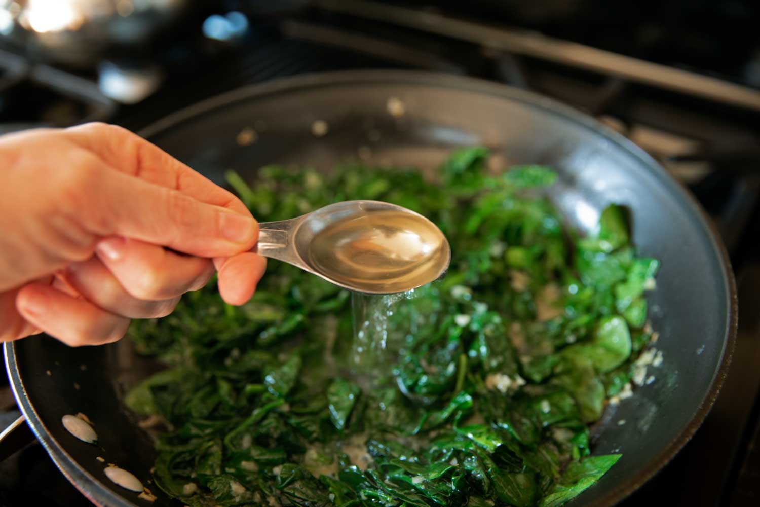 pouring wine into the spinach mixture