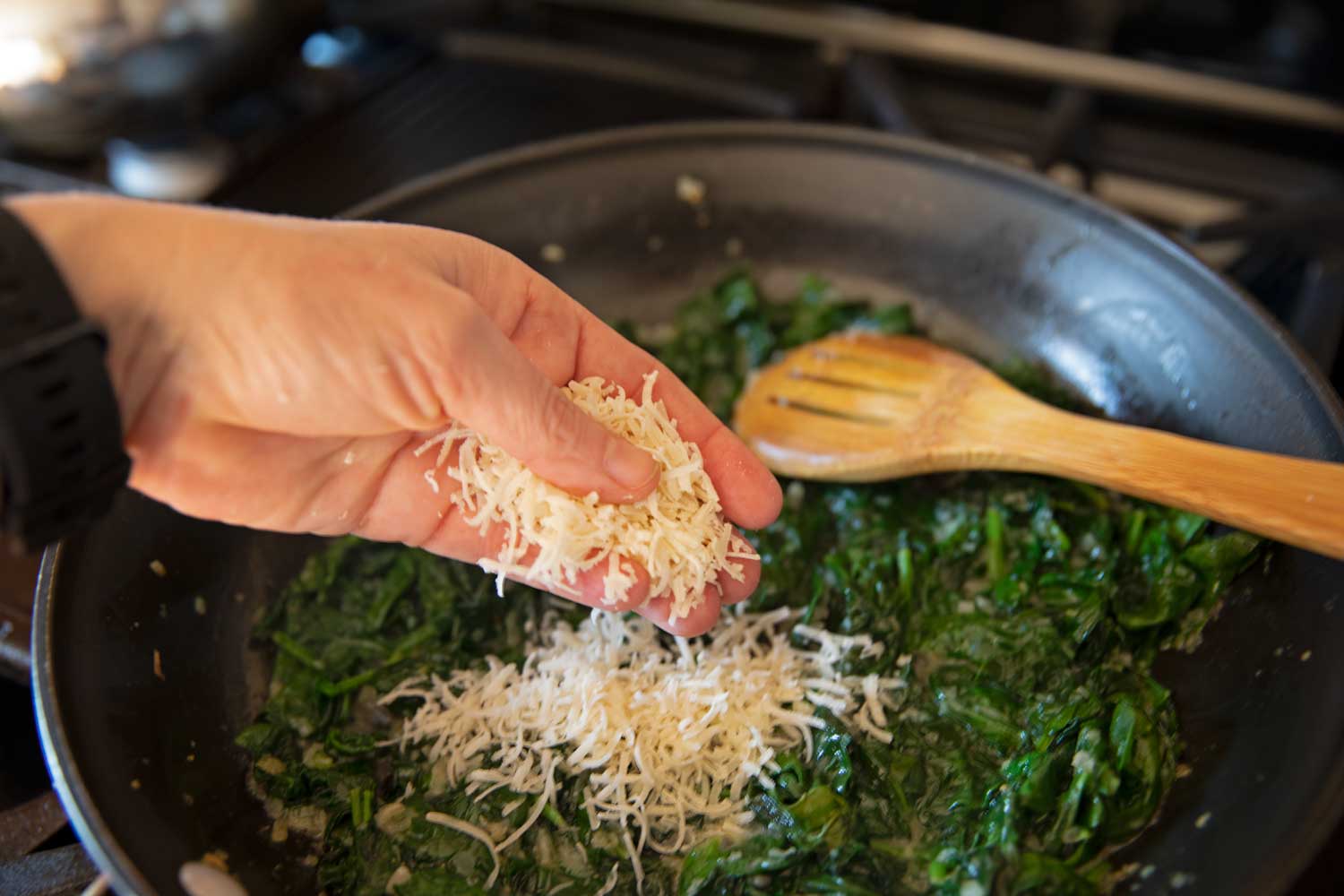 sprinkling cheese into the spinach mixture