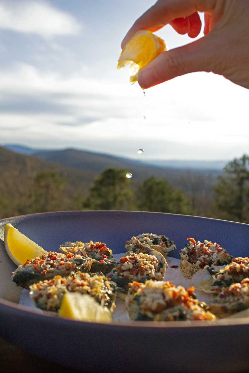 squeezing lemon juice onto oysters Rockefeller
