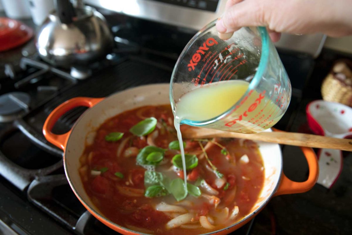 pouring stock into the tomatoes