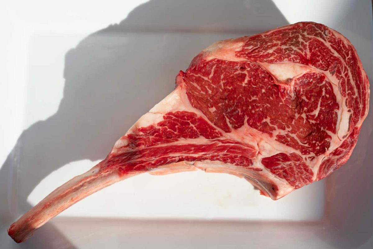 raw tomahawk steak on platter