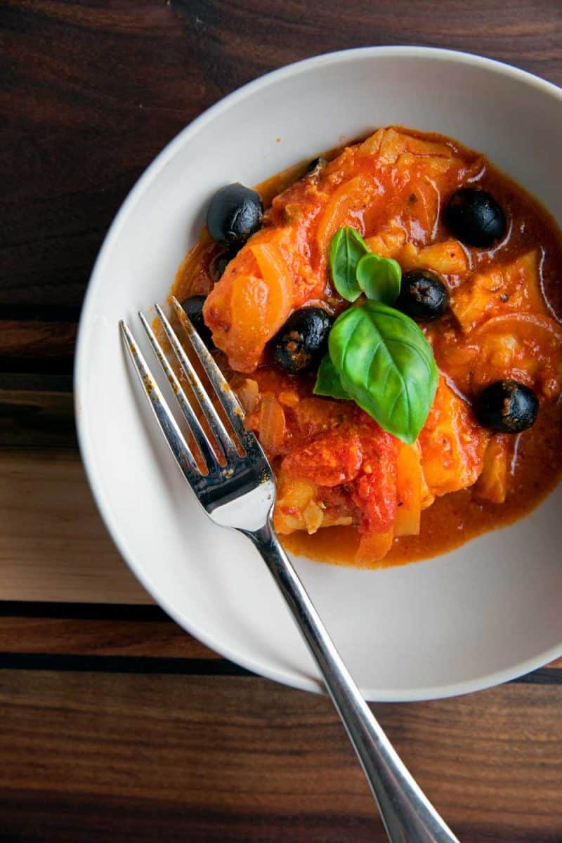serving of fish with tomatoes and olives ready to eat