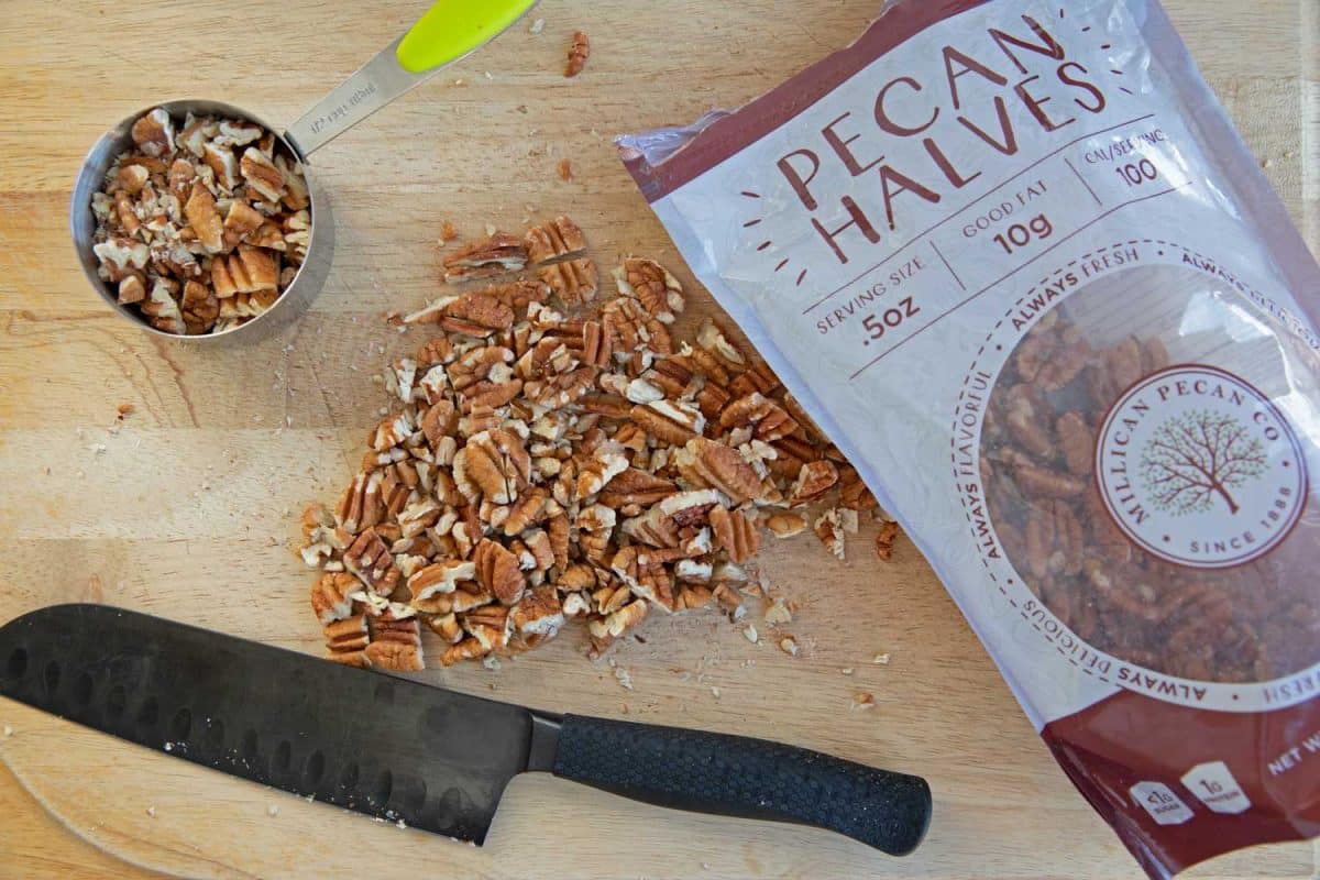 pecans chopped on chopping board with knife and package